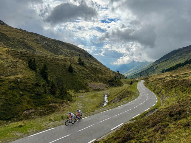 pair of cyclists climb col du Tourmalet through valley on raid pyrenees cycling challenge with marmot tours
