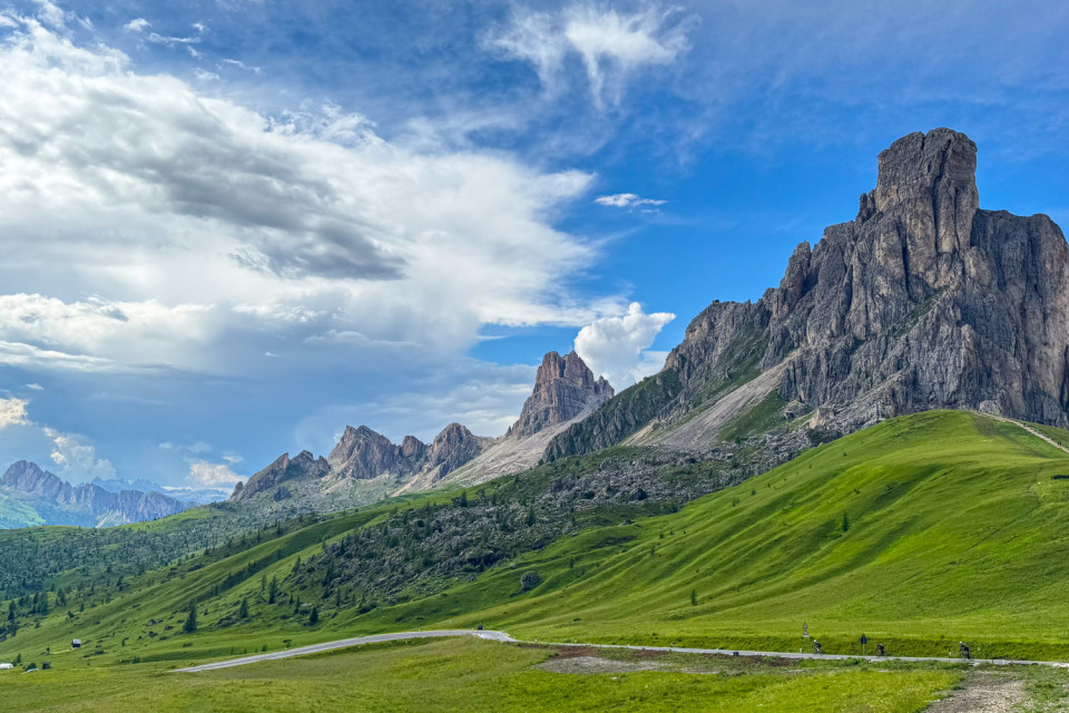 cyclists on passo di Giau cycling climb with towering limestone peaks and green pastures of the dolomites on marmot tours guided cycling holiday