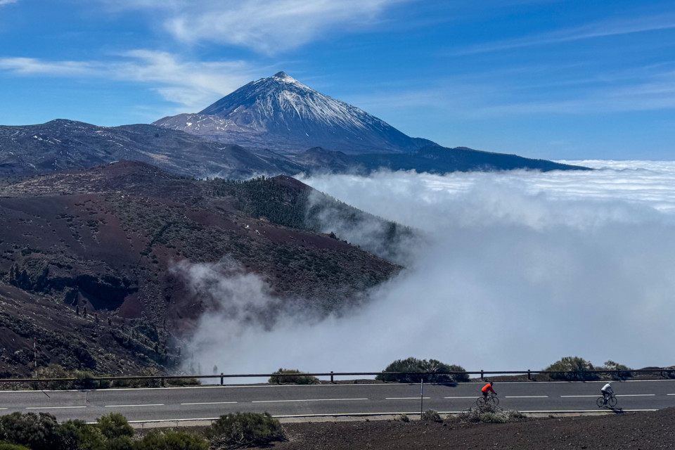 pair of cyclists riding on smooth road in Tenerife with Mount Teide and cloud inversion background beneath blue sky on marmot tours guided cycling tour
