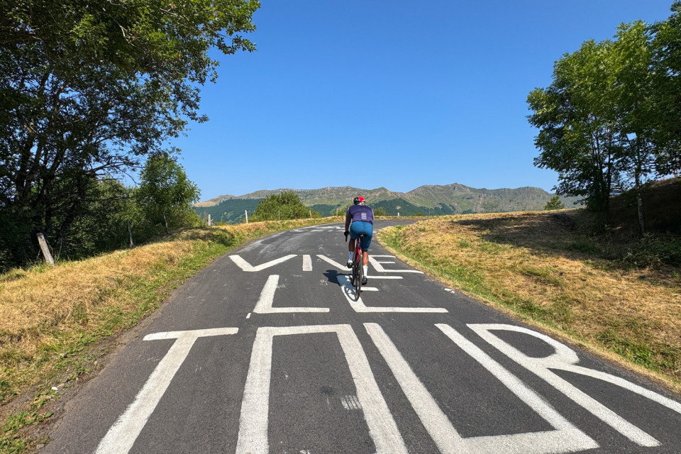cyclist climbing mont aigoual with vive le tour graffiti on road on marmot tours guided road cycling holiday in France