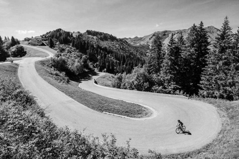 Black and white image of cyclist on Col de Joux Plane switchback with Marmot Tours guided road cycling holidays northern French Alps