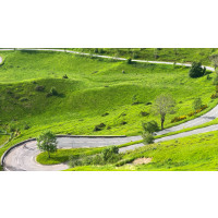 Cyclist on mountain road surrounded by green grass in French pyrenees Col de Peyresourde on Marmot Tours supported cycling tour