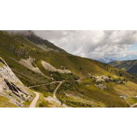 Cyclist climbing Col de l'Iseran in French Alps surrounded by lush pasture and steep mountains on guided road cycling holiday French Alps with Marmot Tours