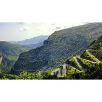 Stacked hairpins of Col de Braus cycling climb and lush slopes of southern French Alps on Marmot Tours guided road cycling holiday in Alps
