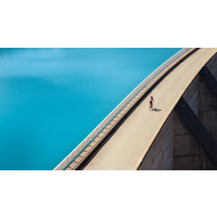 Cyclist crossing dam and reservoir on Cormet de Roselend cycling climb on Marmot Tours French Alps guided cycling holiday