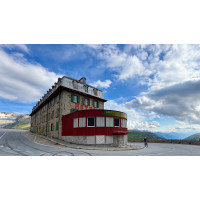 Cyclist rounding corner of Hotel Belvedere switchback on Furkapass cycling in Swiss Alps with Marmot Tours