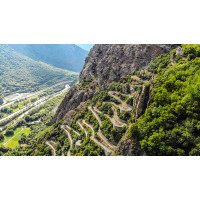 An aerial view of tight switchbacks on a very steep mountainside surrounded by cliffs and green vegetation Marmot Tours French Alps cycling tour