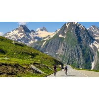 Group of cyclists climbing Nufenen Pass with north face of the Eiger backdrop in Swiss Alps on Marmot Tours cycling holiday