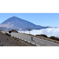 Cyclist descending smooth road with Mt Teide back drop and cloud inversion against blue sky on Marmot Tours guided road cycling holiday tenerife