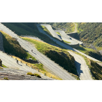 Cyclists on cobbled hairpins of a twisting mountain road in Swiss Alps on Marmot Tours full support cycling tour